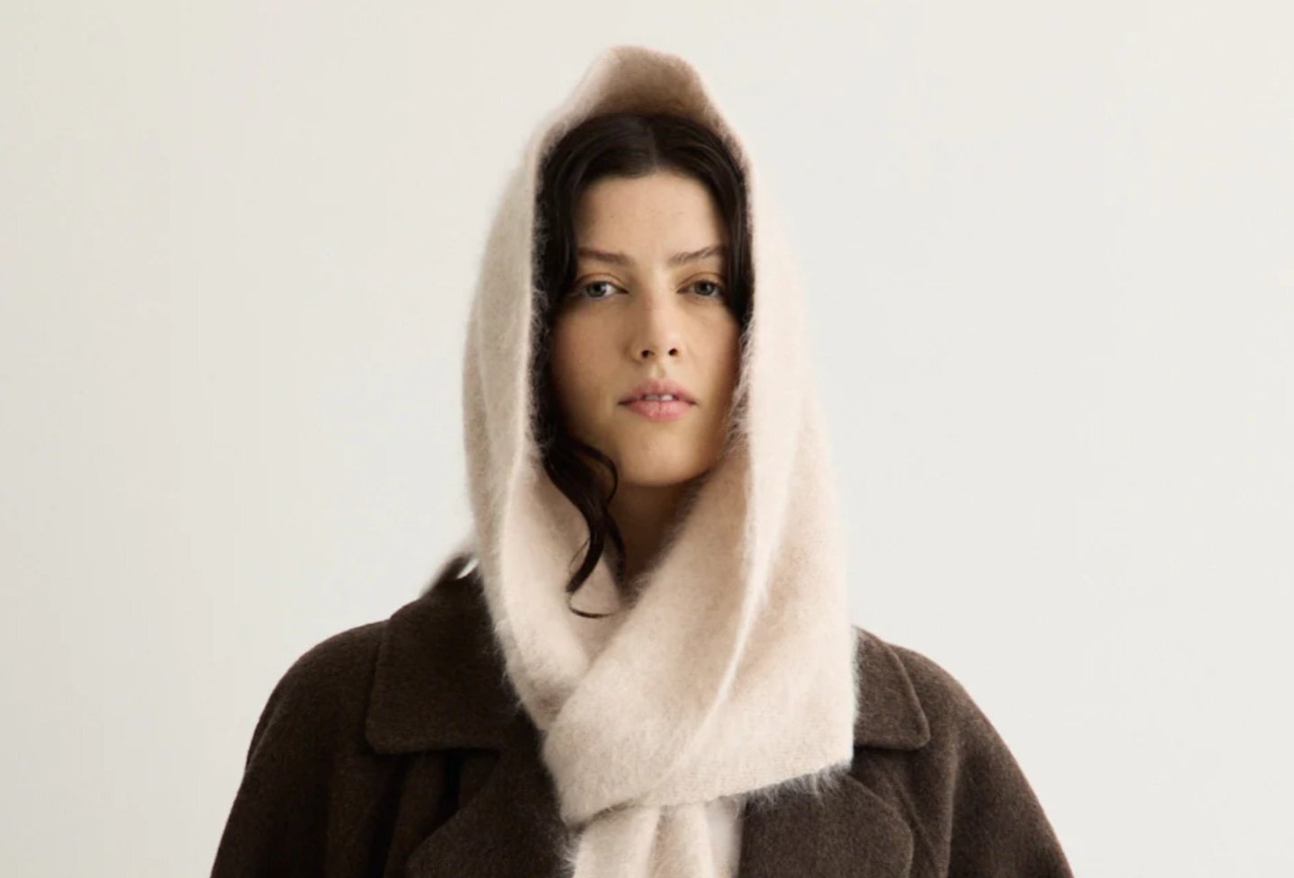 A person is wearing a hooded cream scarf