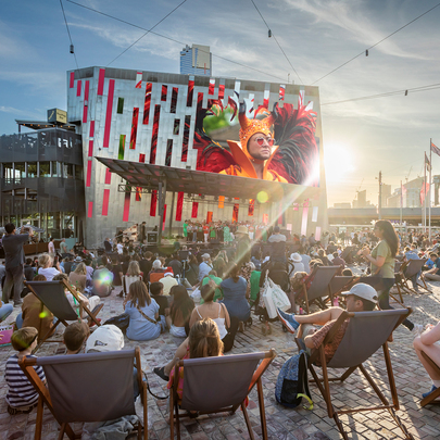 People on deck chairs watching a movie in Fed Square on a large screen.