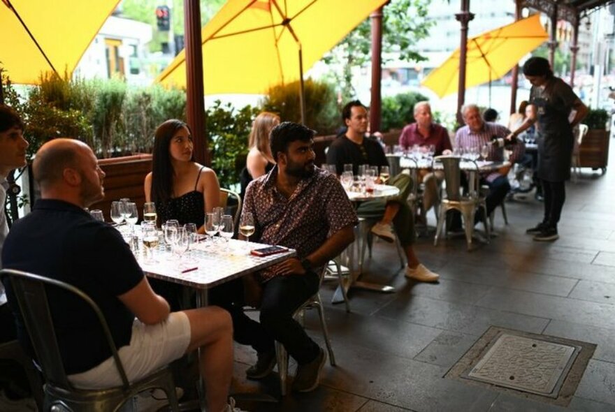 People dining outside under yellow umbrellas. 