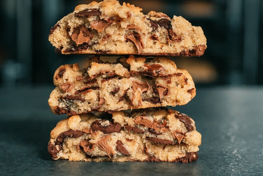 Three choc-chip cookies, broken in half, stacked on top of each other.