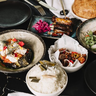 An assortment of Asian-fusion dishes spread across a dark table.