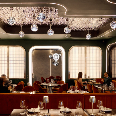 A modern restaurant with glam light fixtures and velvet booths.