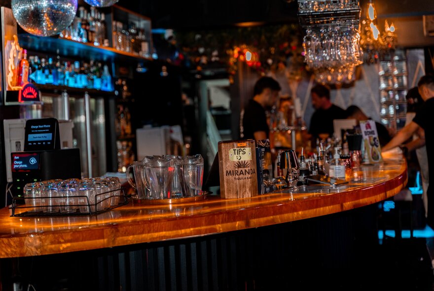 Interior of Miranda Bar with a curved bar and bar staff making drinks.