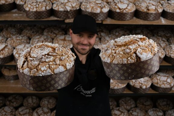 An employee at Brunetti's holding up two panettone festive cakes.