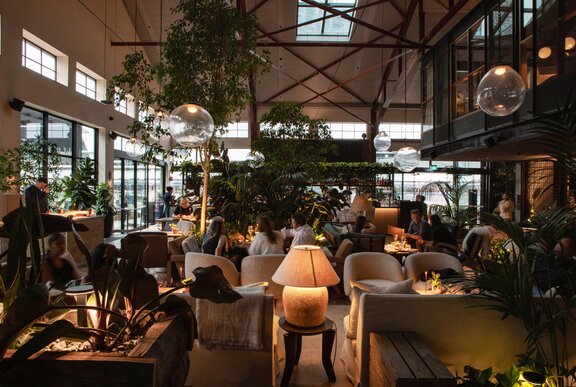 A restaurant with warm lighting and lots of greenery.