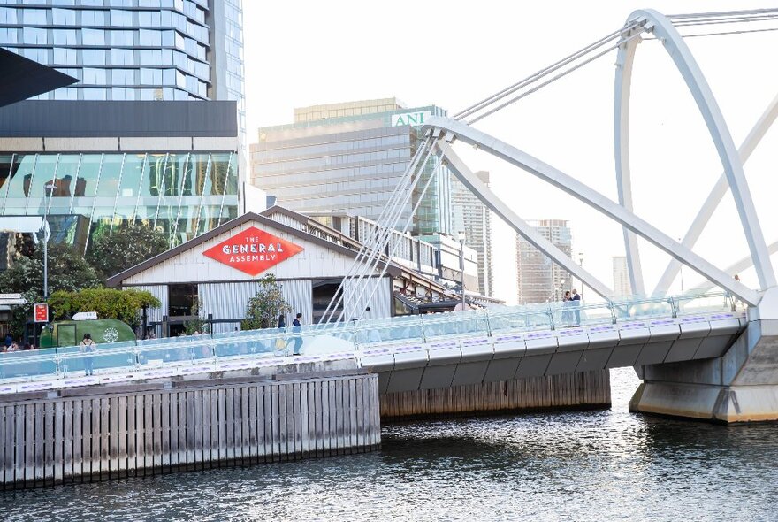 Boatshed pub exterior by day beside a bridge and walkway on the water.