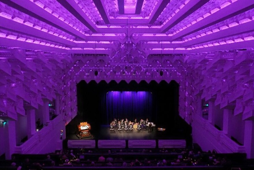 The art deco interior of The Capitol Theatre, lit up in purple lights. 