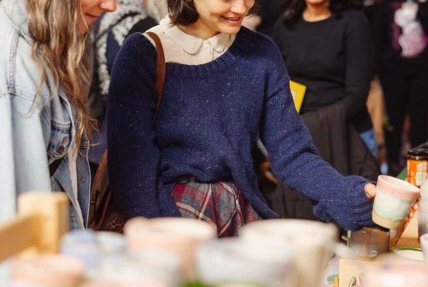 Someone lookingn at ceramic cups at a market stall. 
