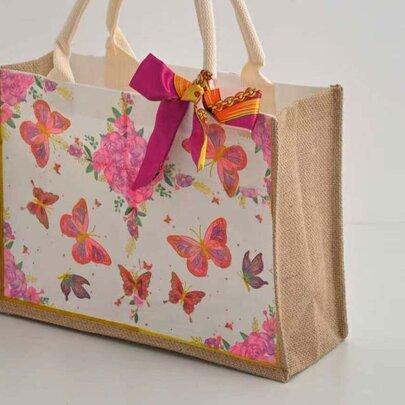 A tote bag decorated in butterflies and a pink ribbon using decoupage techniques