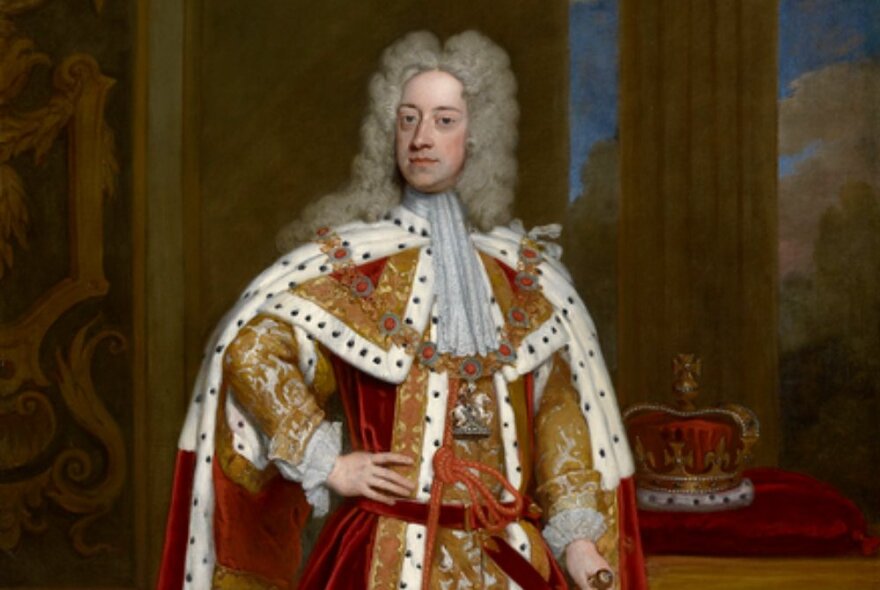 George I wearing ornate gold and ermine robes and wig, standing with hand on hip in front of pillars and his crown.