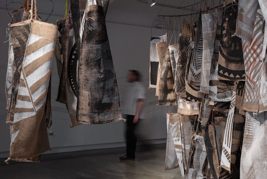 Indigenous textile artworks hanging suspended in a gallery space.