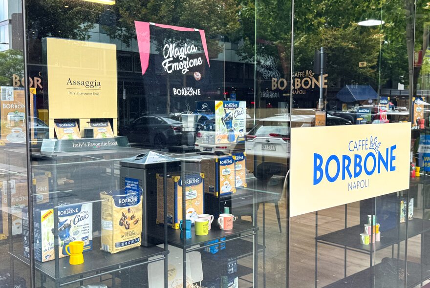 A close up of the window display at Assaggia, Italian produce store, wich Caffe Borbone coffee products on shelves.