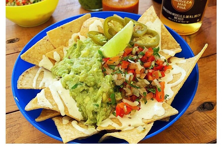 Mexican meal of nachos, guacamole, salsa and chillies.