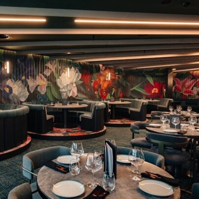 Restaurant interior with dining booths, floral decor and dark lighting.