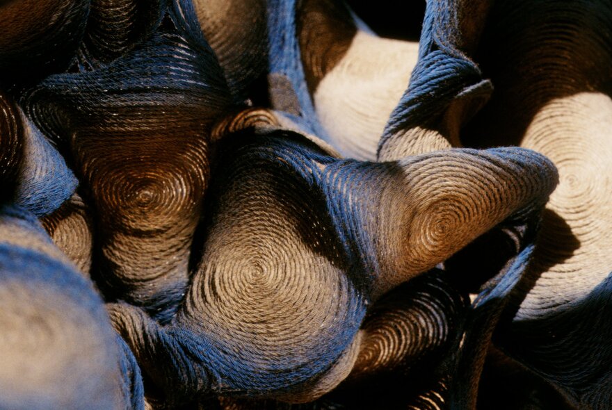 Close-up of coiled objects with blue and brown colouring and a prominent spiral texture, possibly woven textiles.