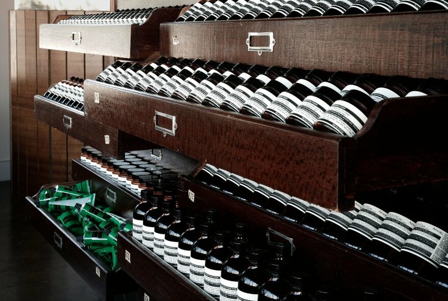 A display of Aesop products in wooden drawers in a store setting. 