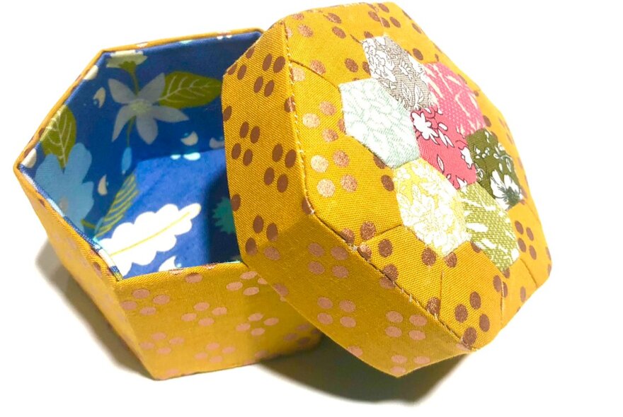A hand crafted yellow trinket box using English paper piecing quilting techniques.