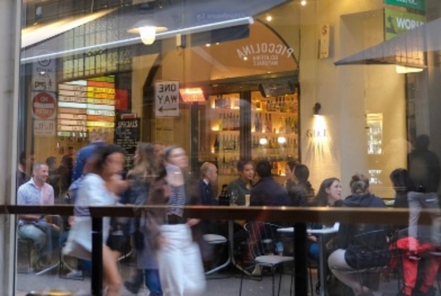 People walking down a lane past diners at restaurant and cafe outdoor tables.