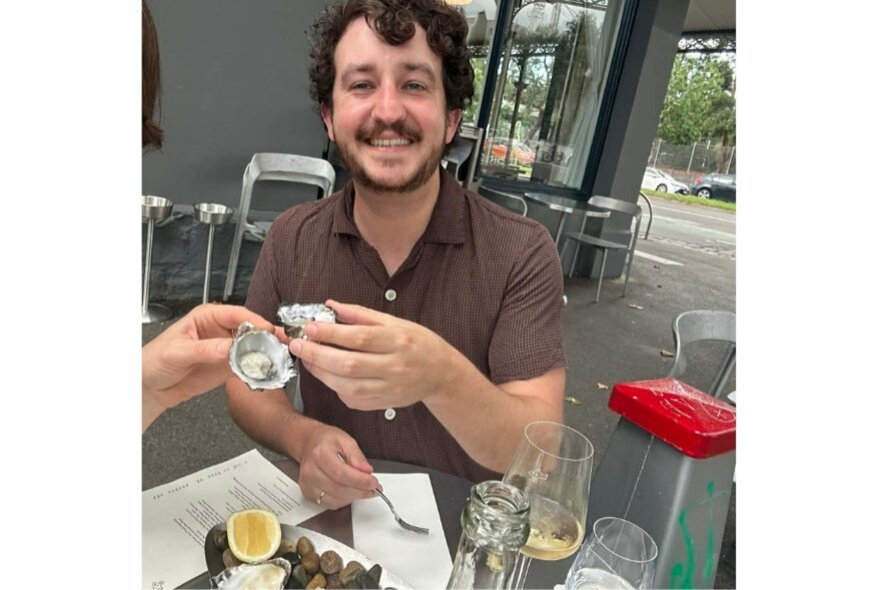 Man cheering a fellow diner with oysters at an outdoor cafe.