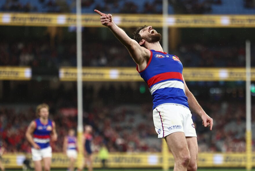 Bulldogs skipper Marcus Bontempelli celebrates a goal with his hand in the air. 