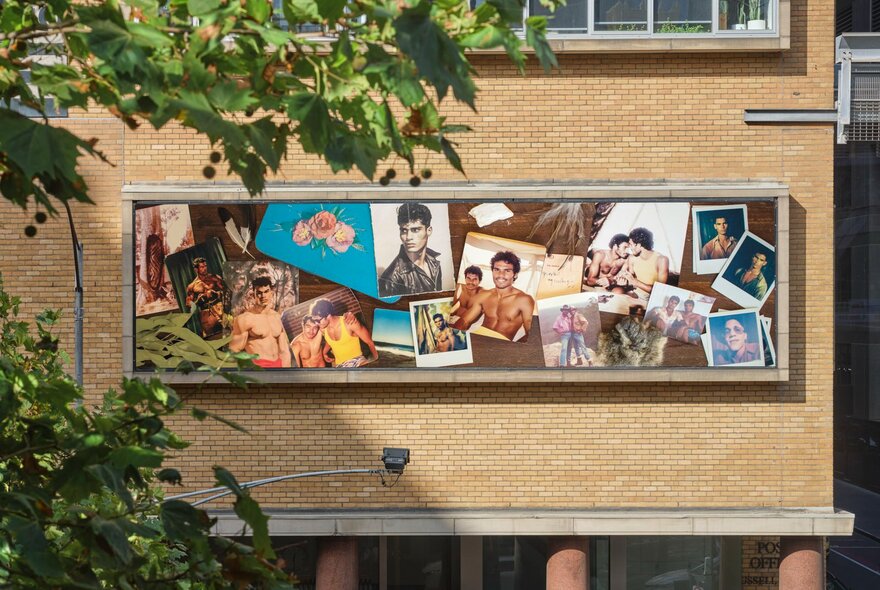 Brightly coloured artwork on the cream brick facade of the Hero apartment building, with a leafy green tree in the foreground.