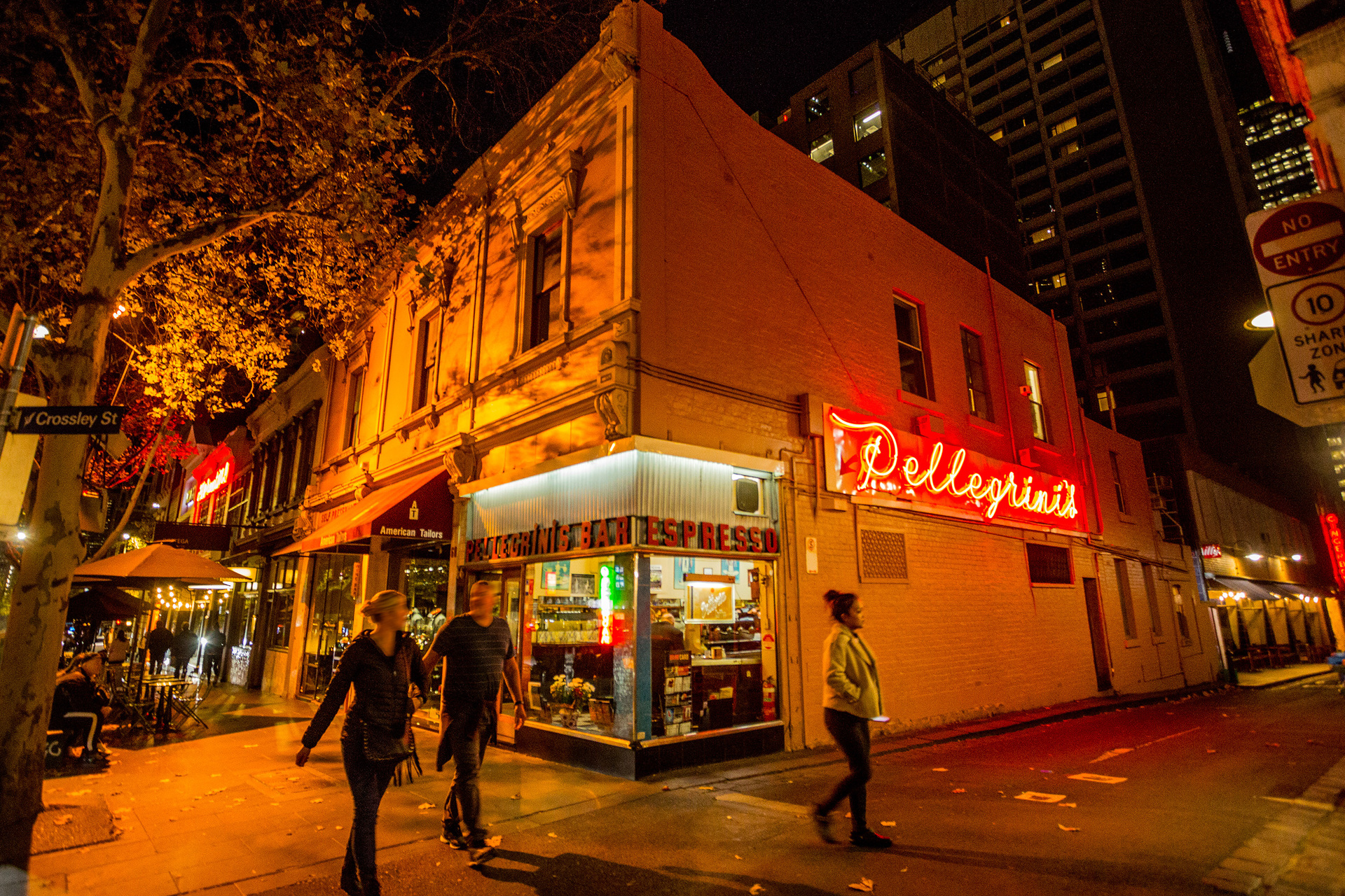 Outside a corner Italian diner at night with a glowing red neon sign saying Pellegrini's