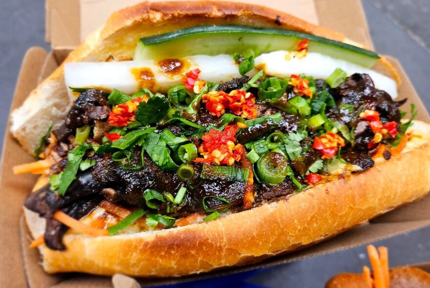 A banh mi loaded with vegetables, chillies and condiments.