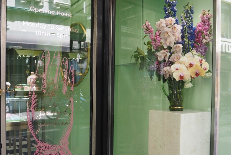 Exterior of Sarah Gardner fine jewellery store, with large glass windows and a bouquet of fresh flowers on a plinth near the entrance.