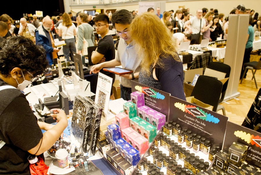 People wandering the stalls at the Melbourne Pen and Stationery Show, looking at products.