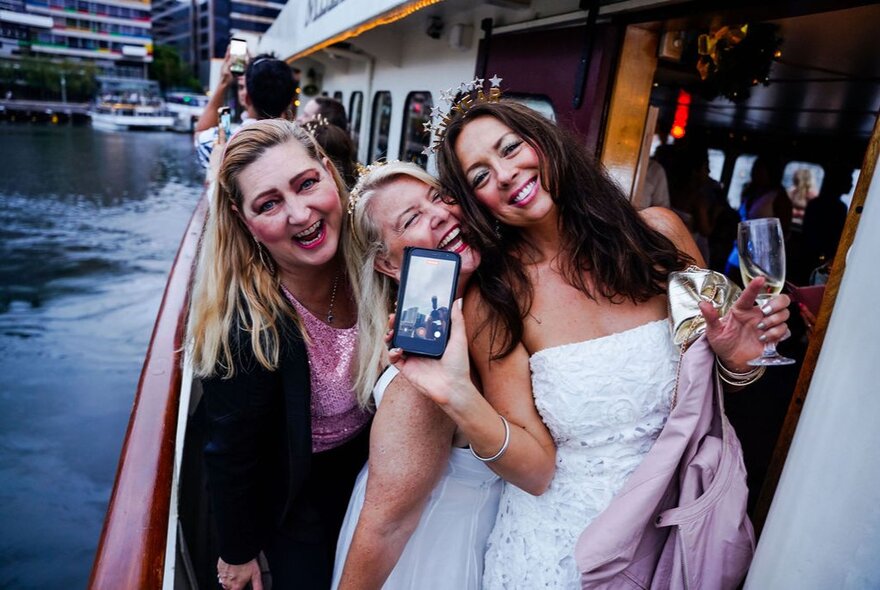 A group of friends smiling and taking a selfie while on a boat trip.