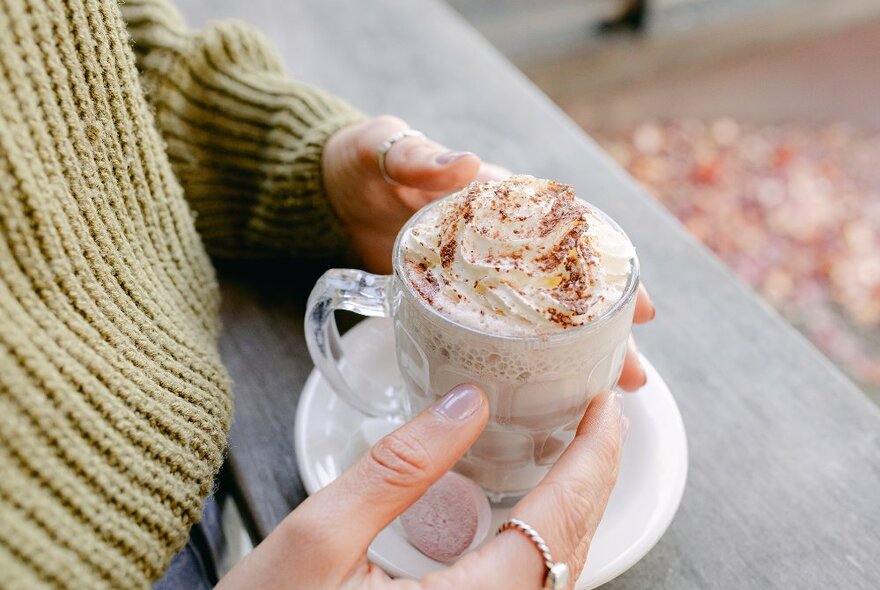 a woman is holding a cup of milo with cream on top