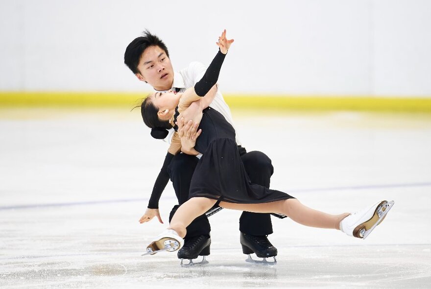 An ice-skating pair executing a daring move on the ice.