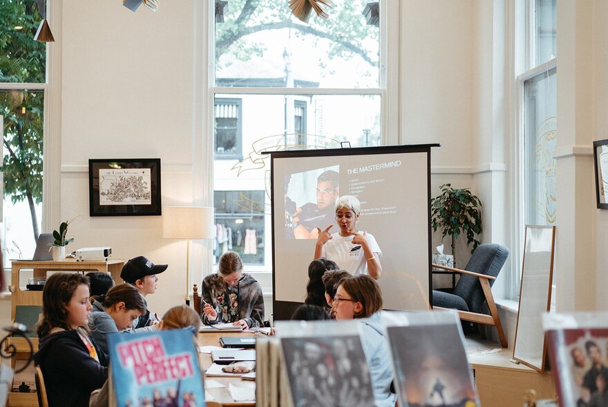 Children seated at a worktable with books and a screen.