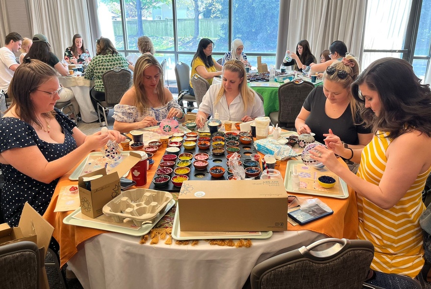 A craft workshop in a studio, with people all heads-down at tables working on projects. 