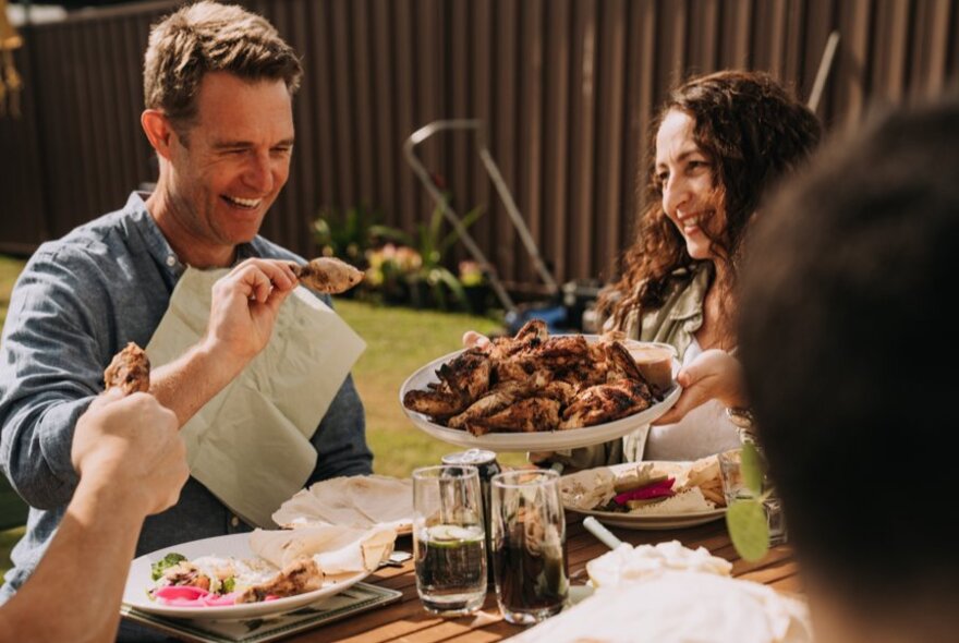 Man eating chicken wearing a bib at an outdoor picnic table.