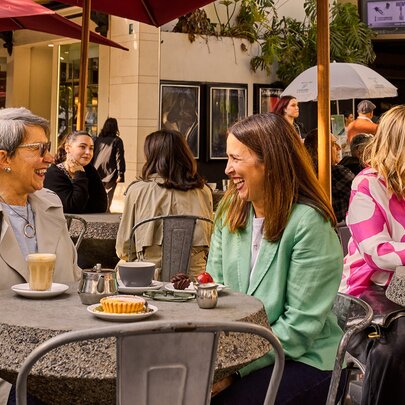 A mother and daughter sharing coffee at an outdoor cafe.