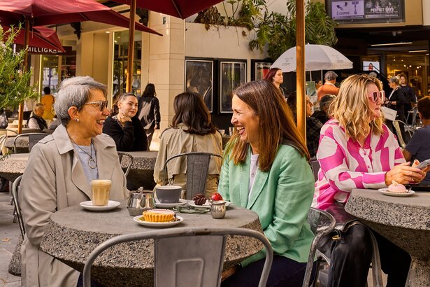 A mother and daughter sharing coffee at an outdoor cafe.