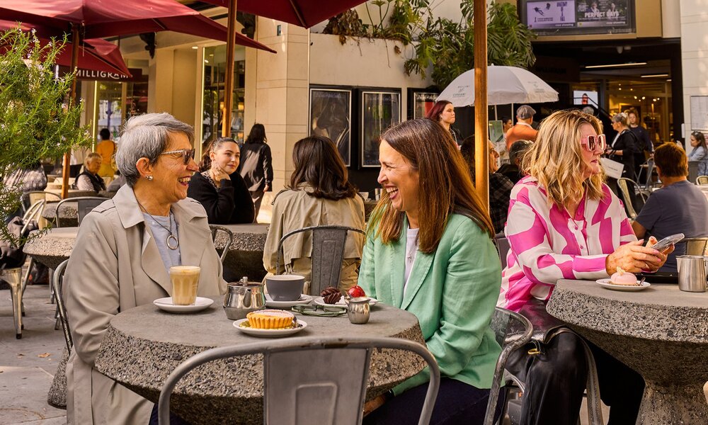 A mother and daughter sharing coffee at an outdoor cafe.