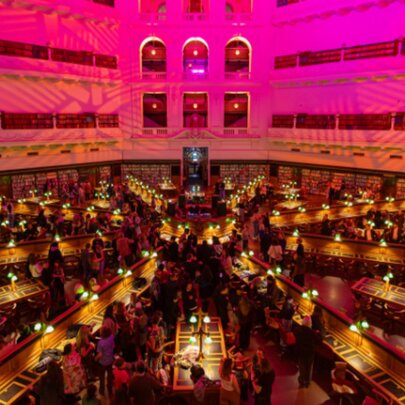State Library Victoria Reading Room lit by pink lights and reading lamps on desks.