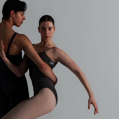 Two ballet dancers intertwined in a movement in subdued light. 