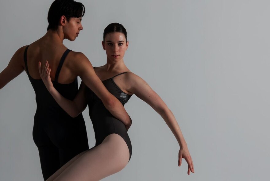 Two ballet dancers intertwined in a movement in subdued light. 