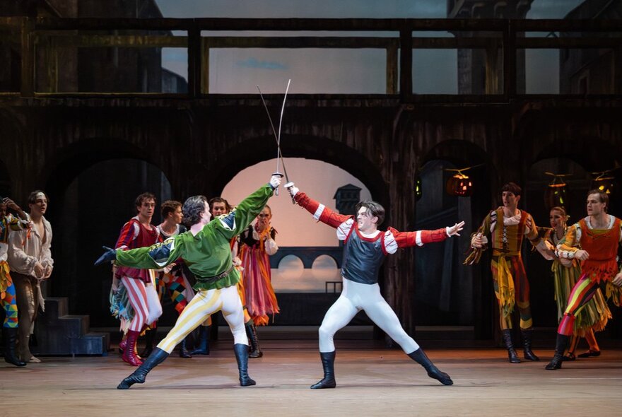 Two male ballet dancers engage in a sword fight on a stage set that resembles a marketplace in Verona, during a performance of Romeo and Juliet by The Australian Ballet.