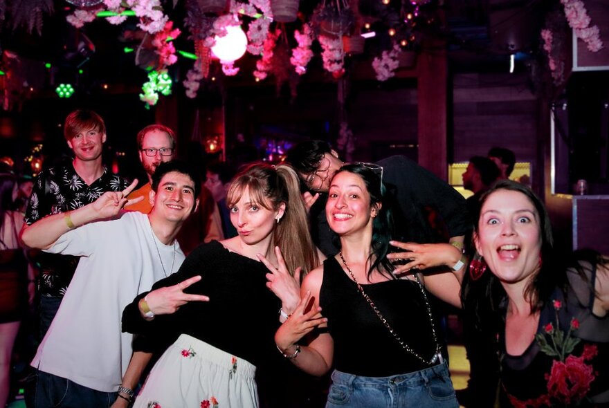 A group of friends at a nightclub smiling and posing for the camera.