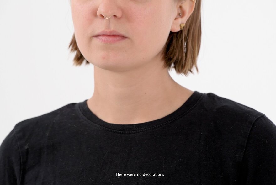 Medium close-up shows a woman with short brown hair and light skin wearing a black top, her eyes are not in the frame.