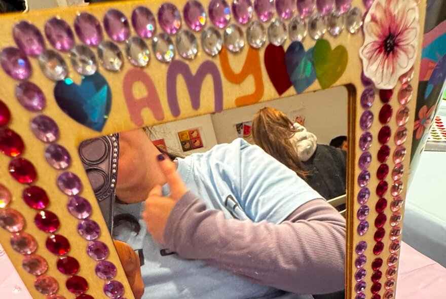 Reflection in a mirror framed with multicoloured gems.