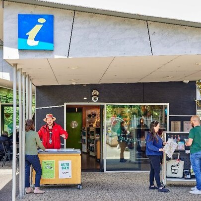 Tourist information centre, with a person in a red uniform talking to a visitor.
