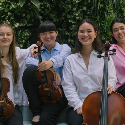 The four members of the Tarilindy Quartet smiling and posing with their instruments. 