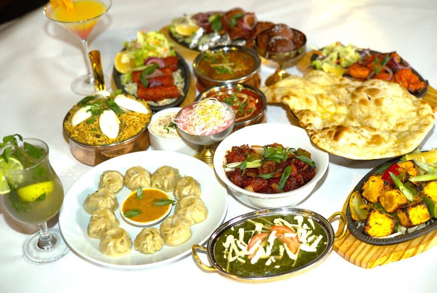 Looking down at a restaurant table with various platters of Indian and Nepali food including bread, rice, curries, and drinks.