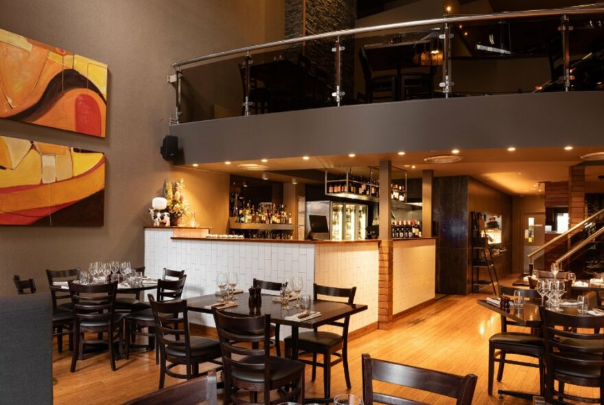 The warm-toned interior of an empty restaurant with tables and a bar