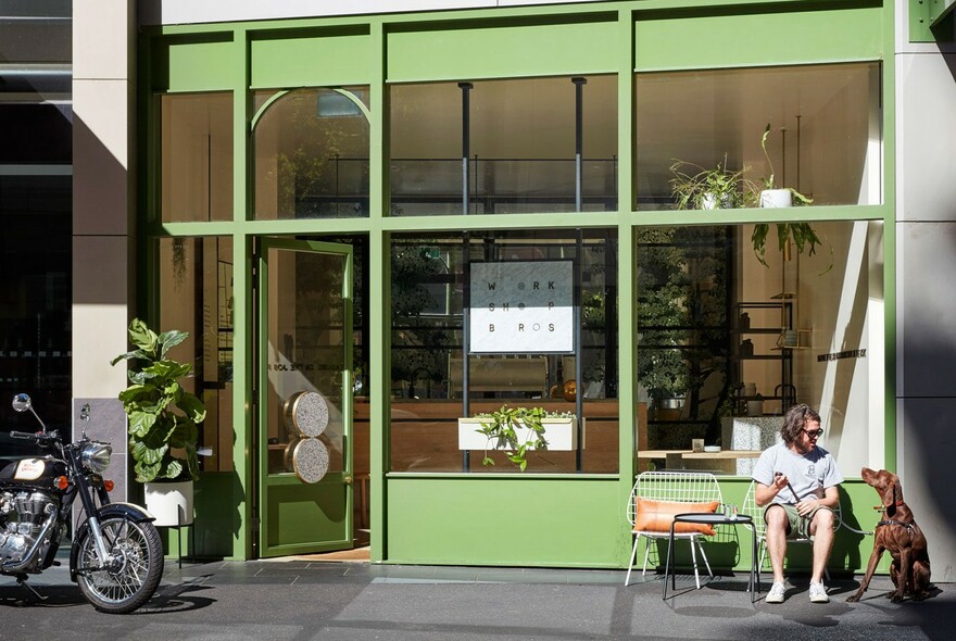 Exterior of Workshop Brothers café with man and his dog at an outside table.